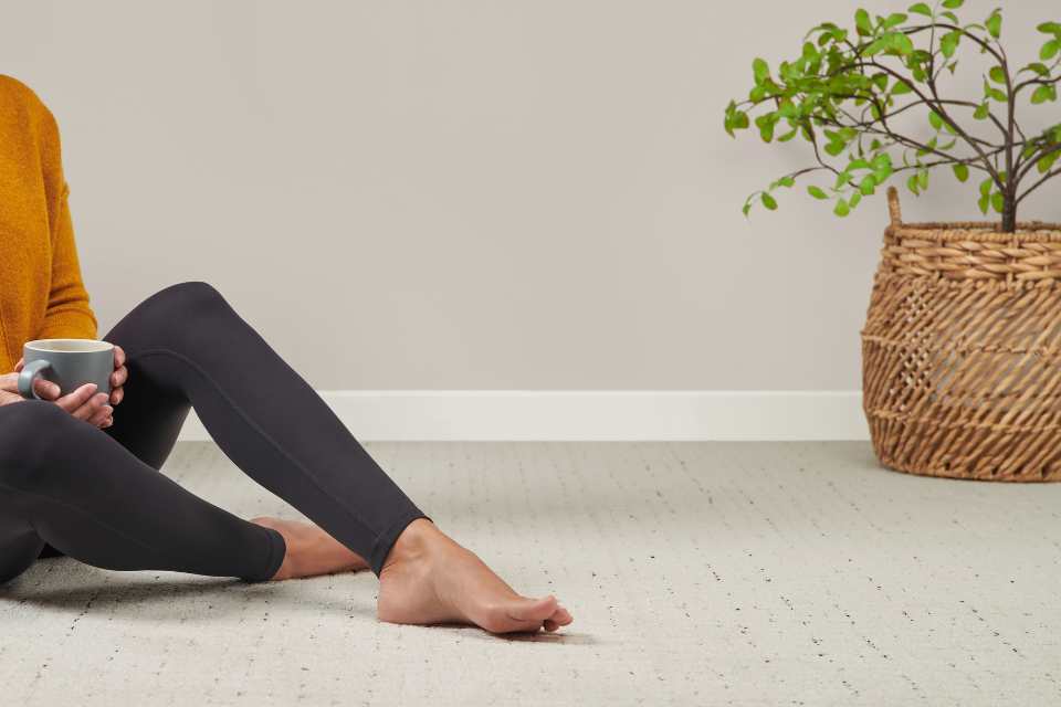 woman sitting on brand new carpeted flooring in clean home with plant in wicker basket